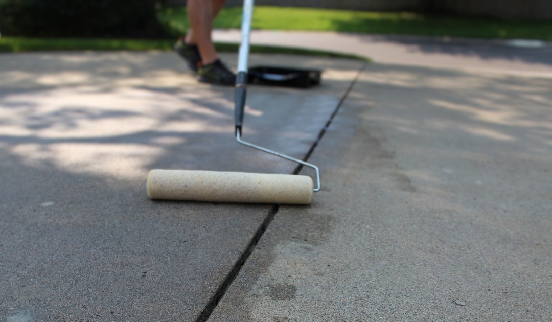 Man Applying Concrete Sealer To A Driveway.